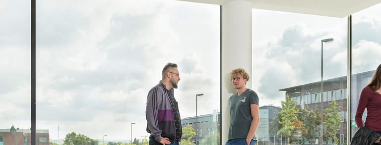 Students are talking in front of a window